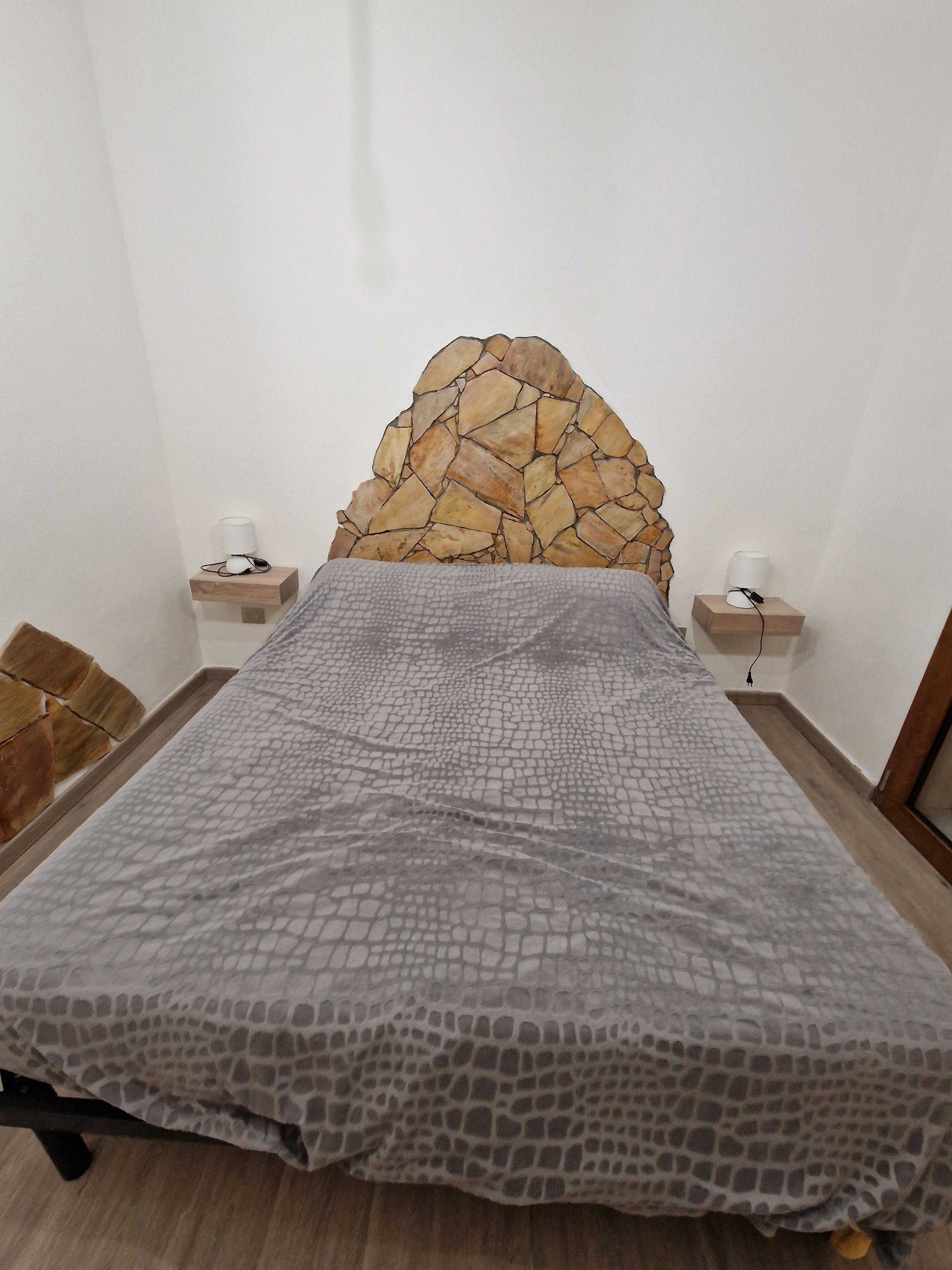 Dettaglio camera da letto con testata in pietra